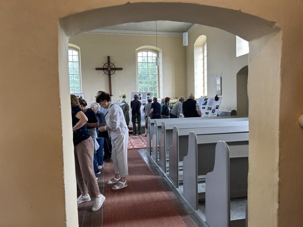 Besucher betrachten die Ausstellung im Innenraum der Dorfkirche