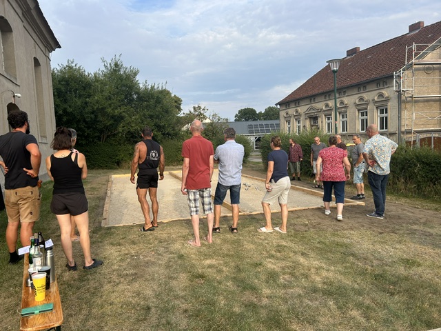 Zuschauer beim Boule-Turnier verfolgen ein Spiel vor der Dorfkirche