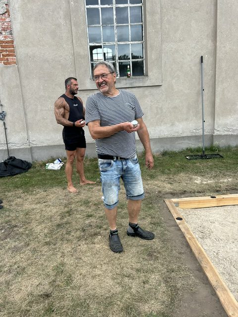 Lachender Spieler mit der Boule-Kugel in der Hand