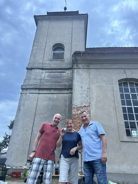 Drei Teilnehmer vor dem Kirchturm